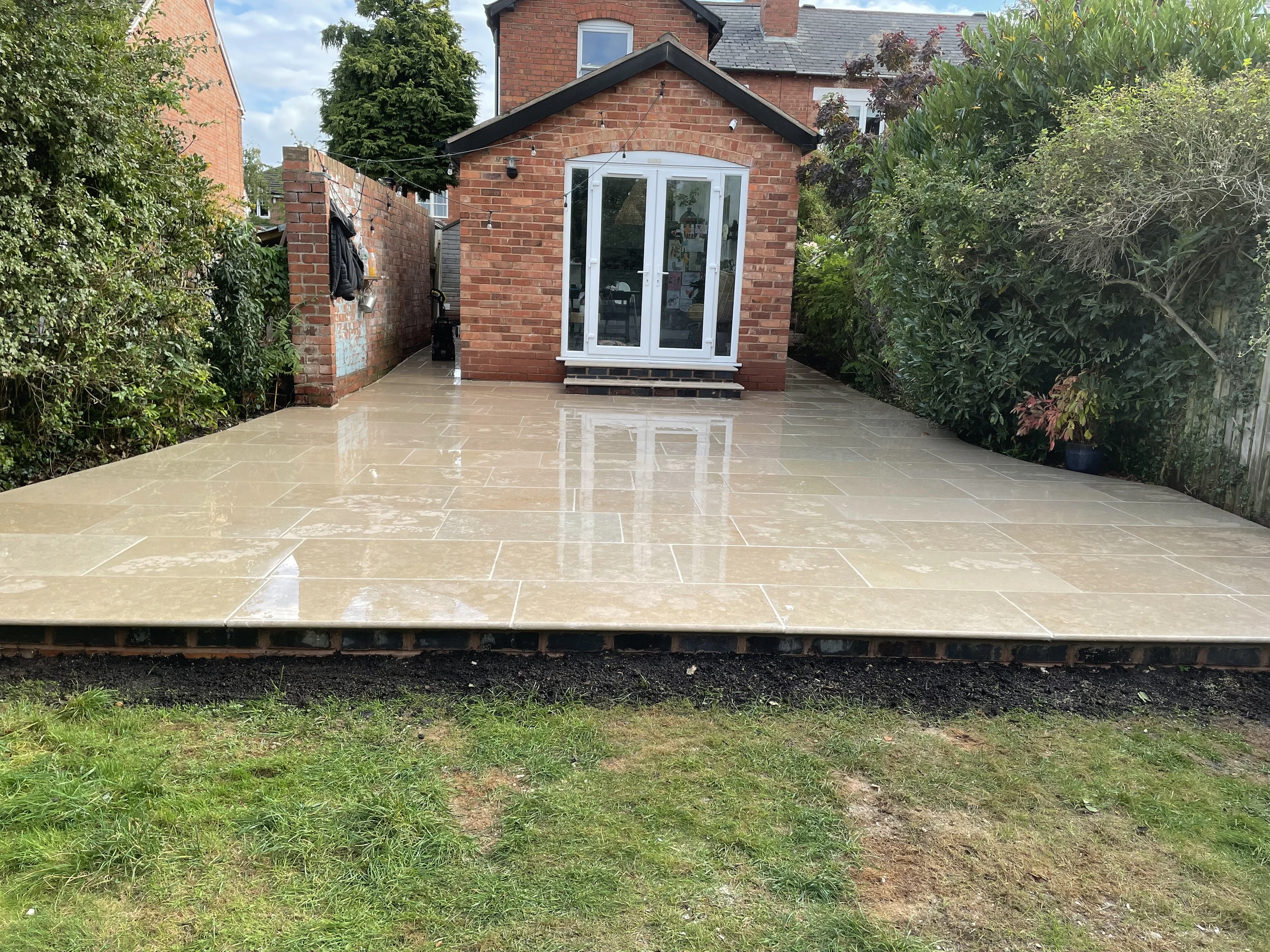 Completed stone garden patio in front of a brick garden building