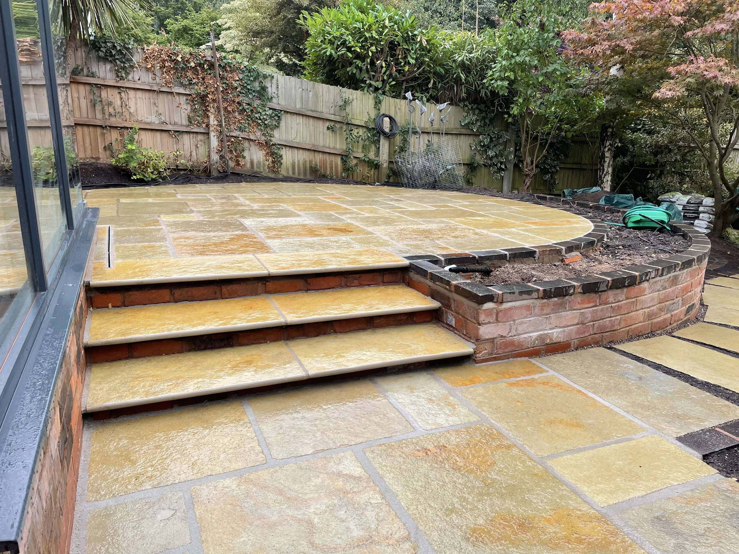 Raised stone patio with broad stone steps and curved brick retaining wall